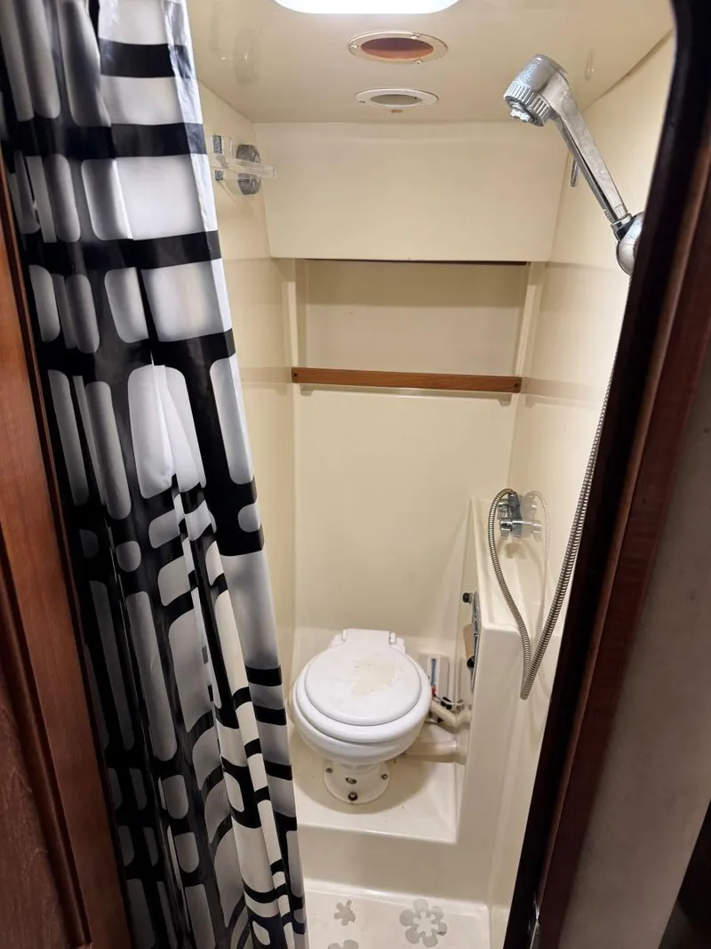 Slide: The Image of 1988 Chris-Craft 426 Catalina bathroom with shower, toilet, and patterned curtain. - 35