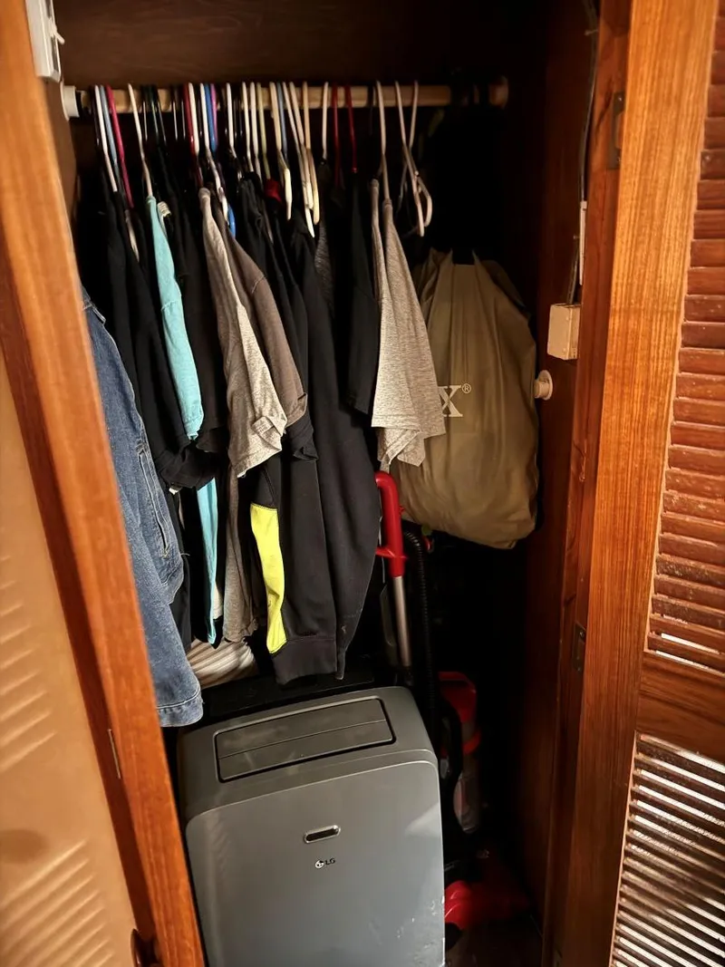 Slide: The Image of A small closet with hanging clothes and a portable air conditioner. - 46