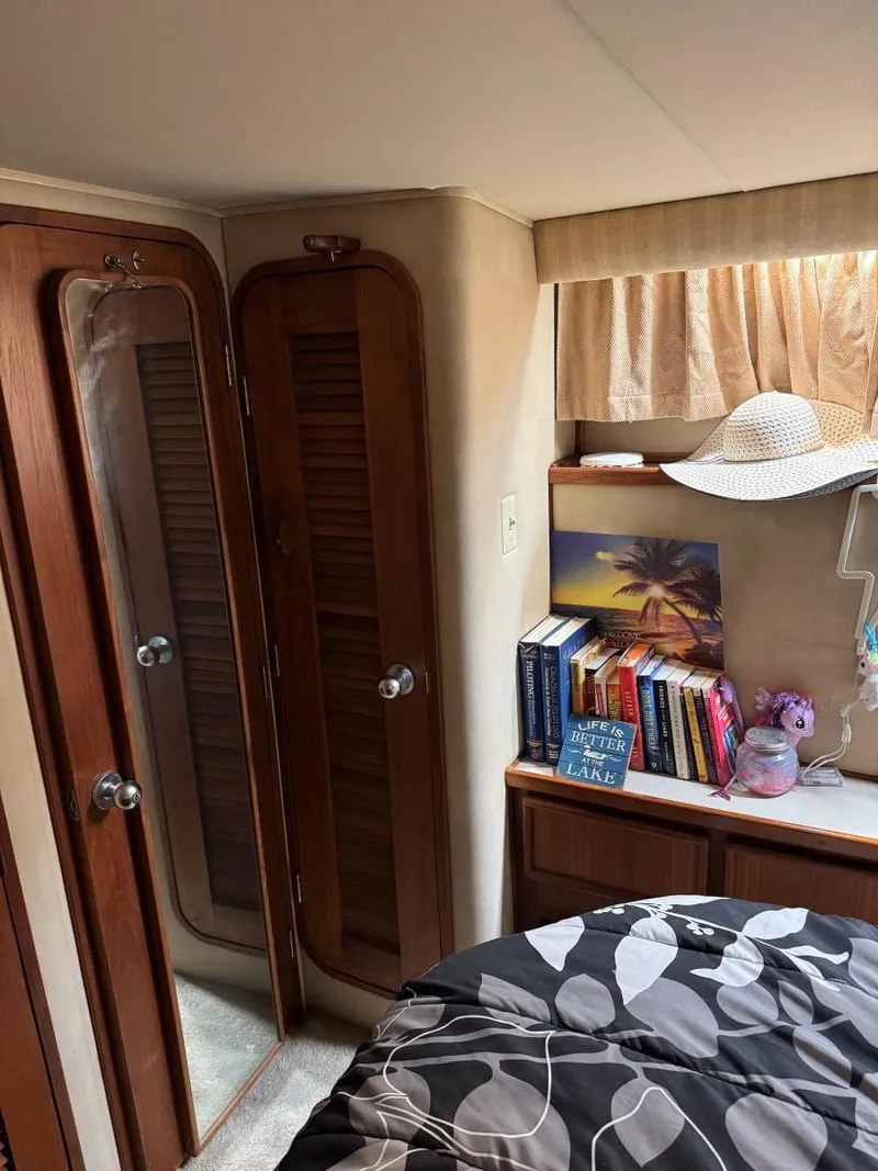 Slide: The Image of 1988 Chris-Craft 426 Catalina cabin interior with books, hat, and floral bedding. - 47