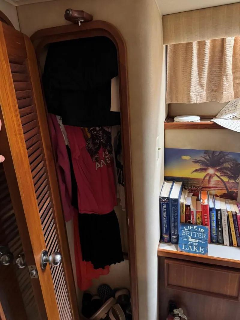Slide: The Image of Interior of 1988 Chris-Craft 426 Catalina with closet and bookshelf, featuring lake-themed decor. - 48