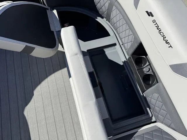 Slide: The Image of 2025 Starcraft CX 23 RL boat interior with storage compartment and cup holders. - 33