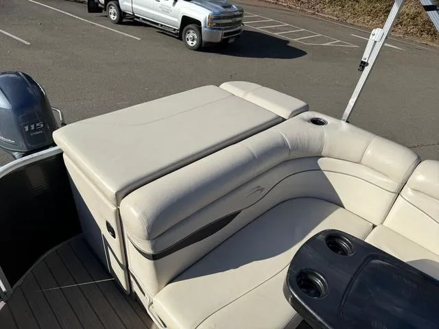 Slide: The Image of 2017 Bennington 20SLMX boat with beige seating and cup holders, parked near a truck. - 7