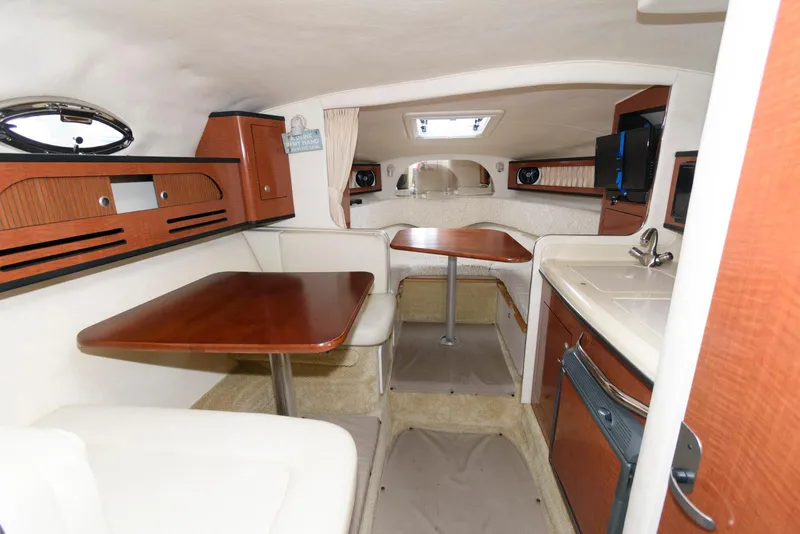 Slide: The Image of Interior of 2005 Sea Ray 280 Sundancer, featuring wood accents and compact dining area. - 12