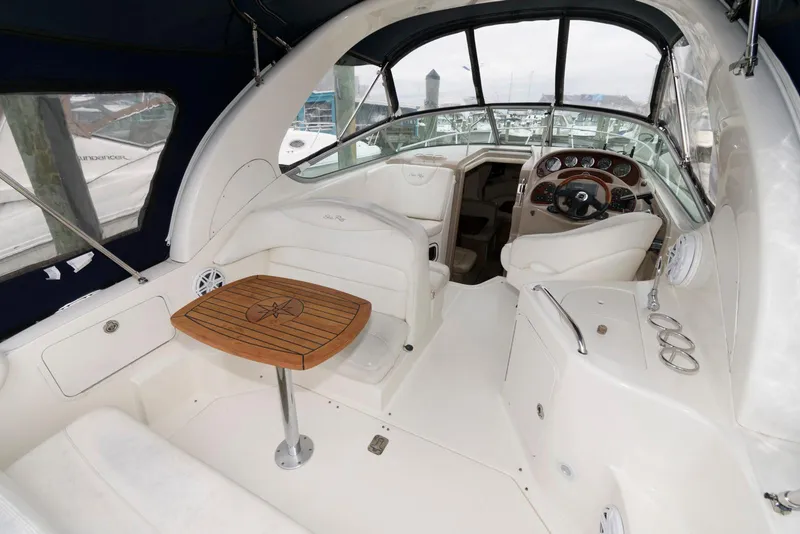 Slide: The Image of 2005 Sea Ray 280 Sundancer boat interior with helm, seating, and wooden table. - 6