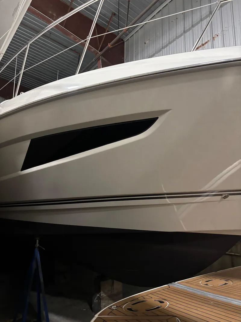 Slide: The Image of 2019 Riviera 4800 Sport Yacht in storage, showcasing sleek hull design. - 2
