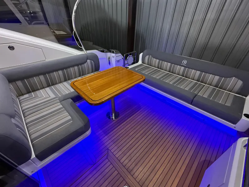 Slide: The Image of 2019 Riviera 4800 Sport Yacht interior with striped seating, wooden table, and blue LED lighting. - 21