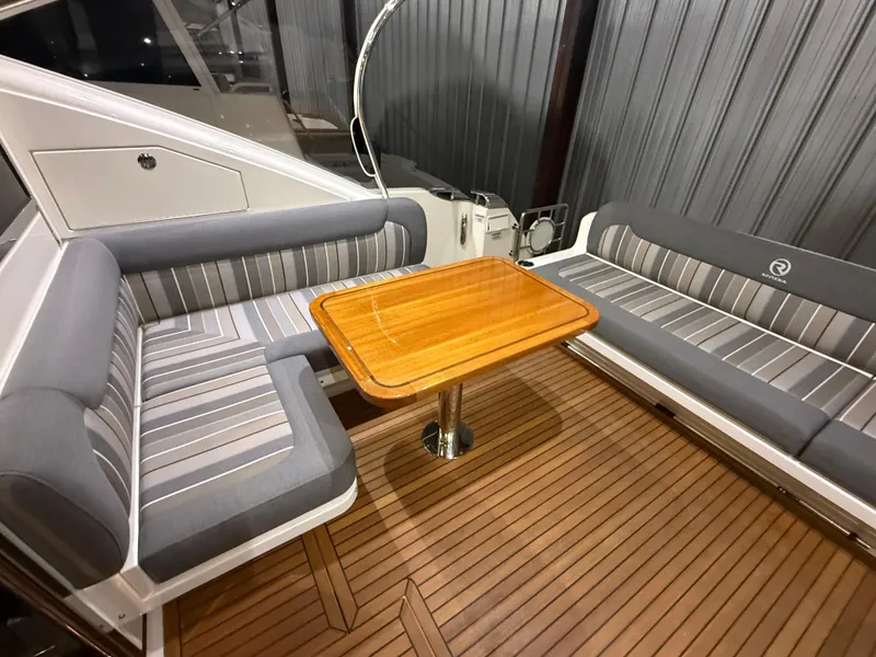 Slide: The Image of Luxurious seating area on 2019 Riviera 4800 Sport Yacht with wooden table and striped cushions. - 23