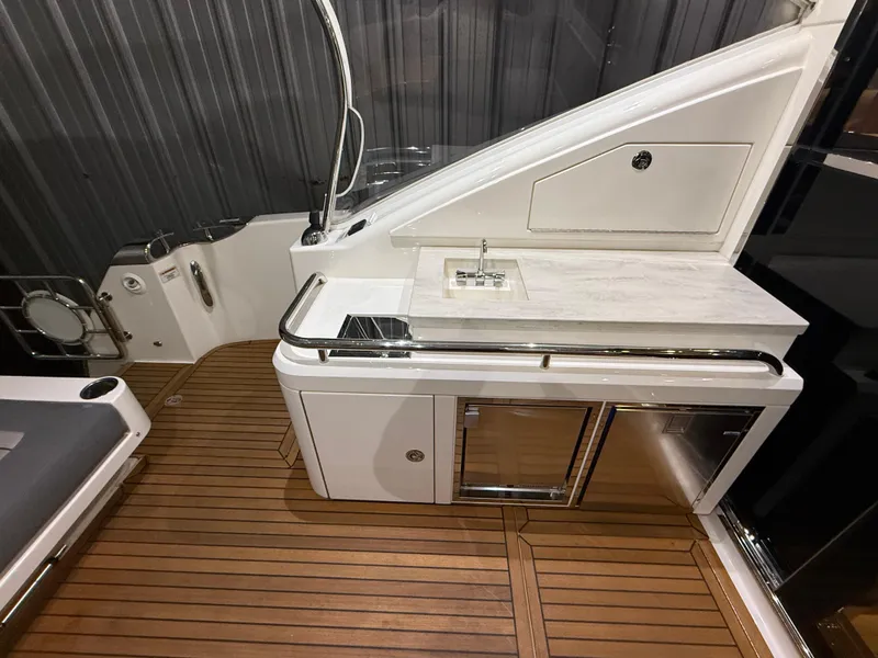 Slide: The Image of 2019 Riviera 4800 Sport Yacht interior with wooden flooring and sleek kitchenette. - 26