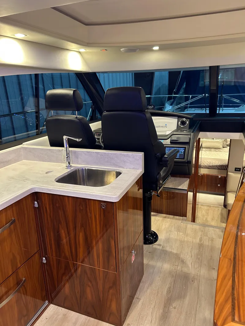 Slide: The Image of Interior of 2019 Riviera 4800 Sport Yacht with helm and kitchenette. - 32