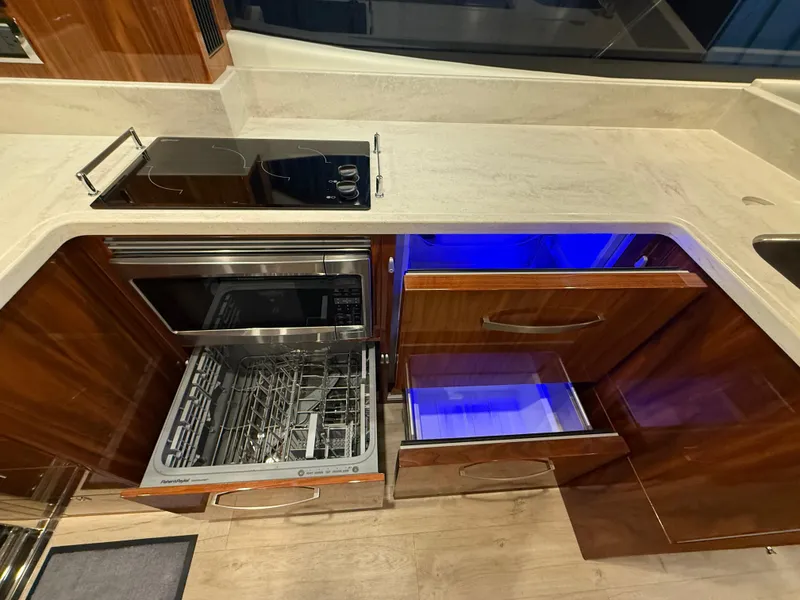 Slide: The Image of Modern kitchen in 2019 Riviera 4800 Sport Yacht with stove, dishwasher, and wooden cabinetry. - 33