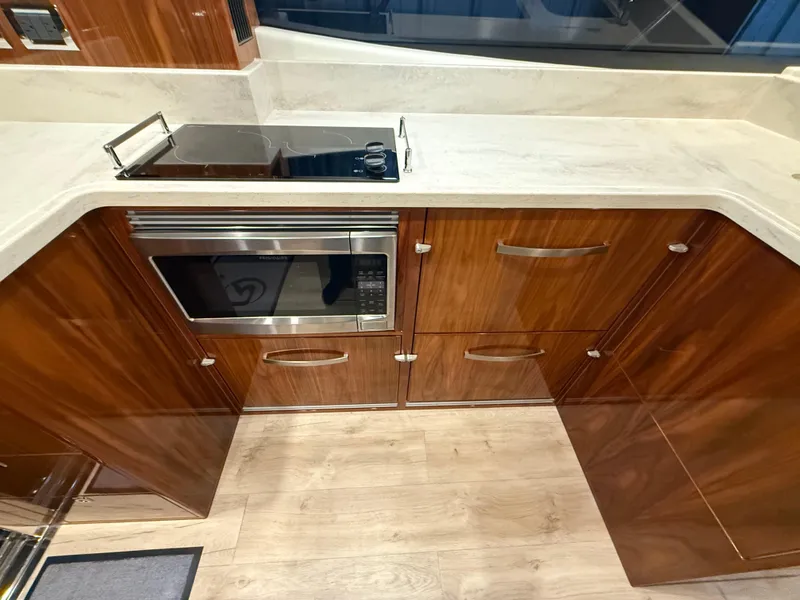 Slide: The Image of Modern kitchen in 2019 Riviera 4800 Sport Yacht with wood cabinetry and appliances. - 34