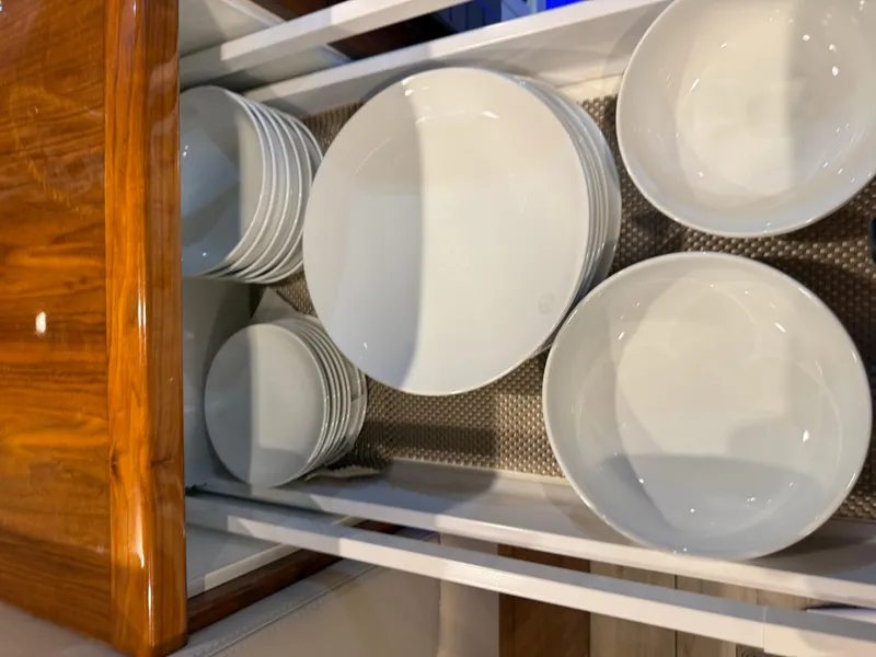 Slide: The Image of White dishes neatly arranged in a wooden drawer on a 2019 Riviera 4800 Sport Yacht. - 44