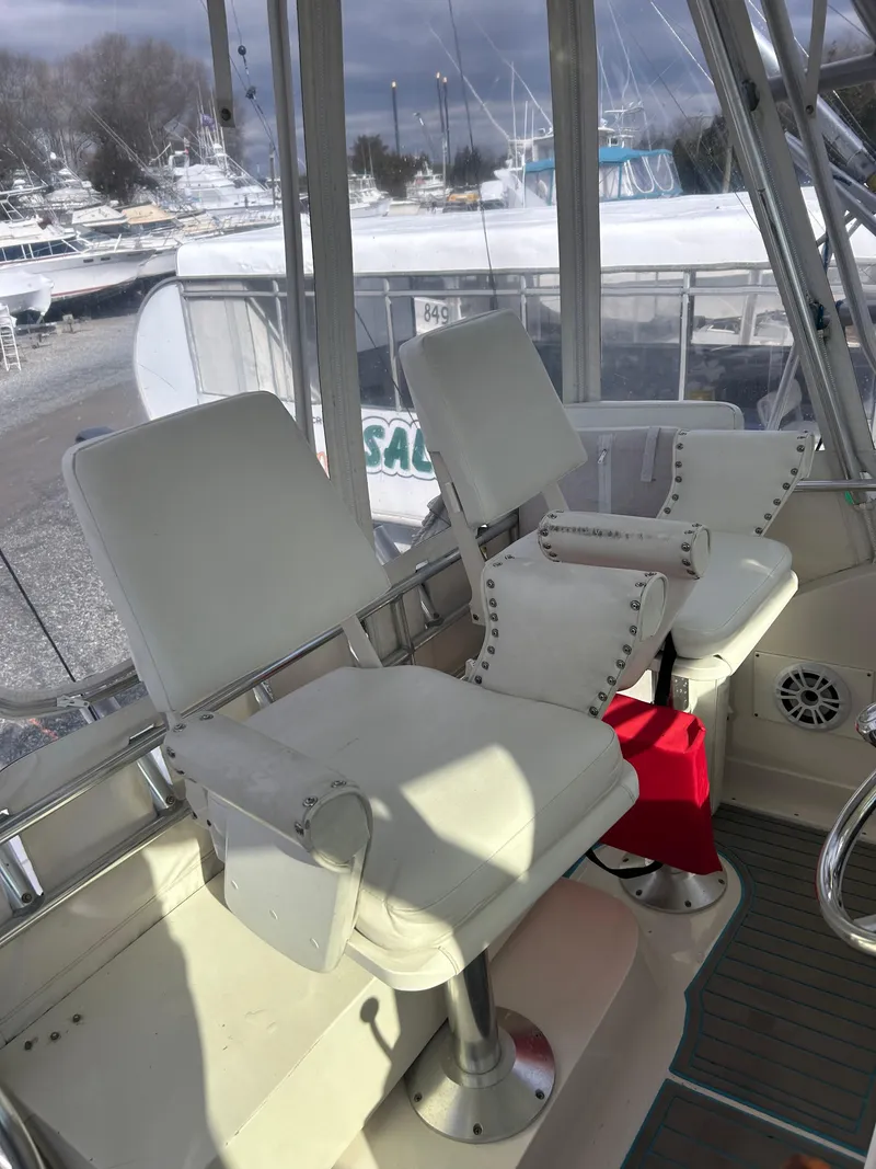 Slide: The Image of 1995 Blackfin 33 Convertible boat interior with white captain chairs and marina view. - 23