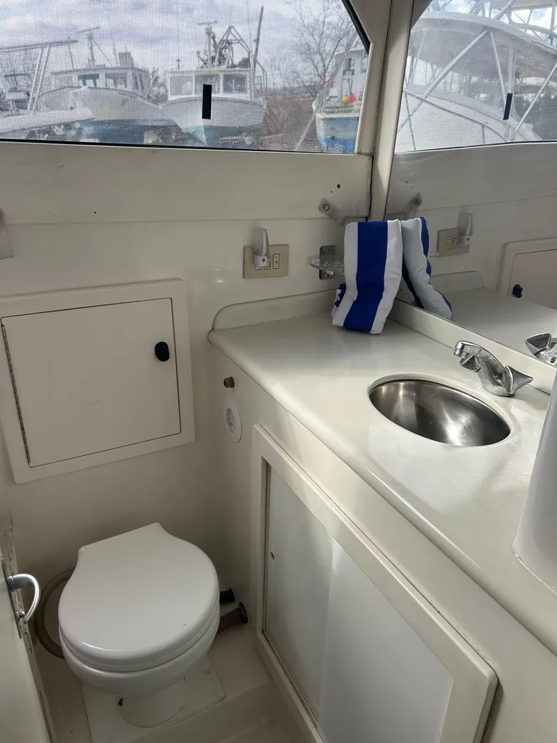 Slide: The Image of 1995 Blackfin 33 Convertible boat bathroom with sink, toilet, and storage cabinet. - 33