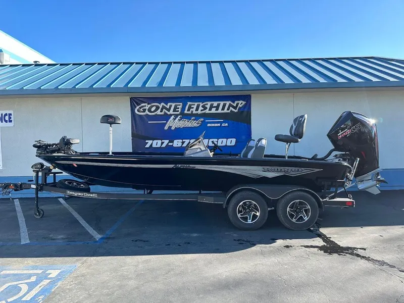 Slide: The Image of 2025 Ranger ALPHA 208 boat on trailer, parked outside a fishing store. - 0