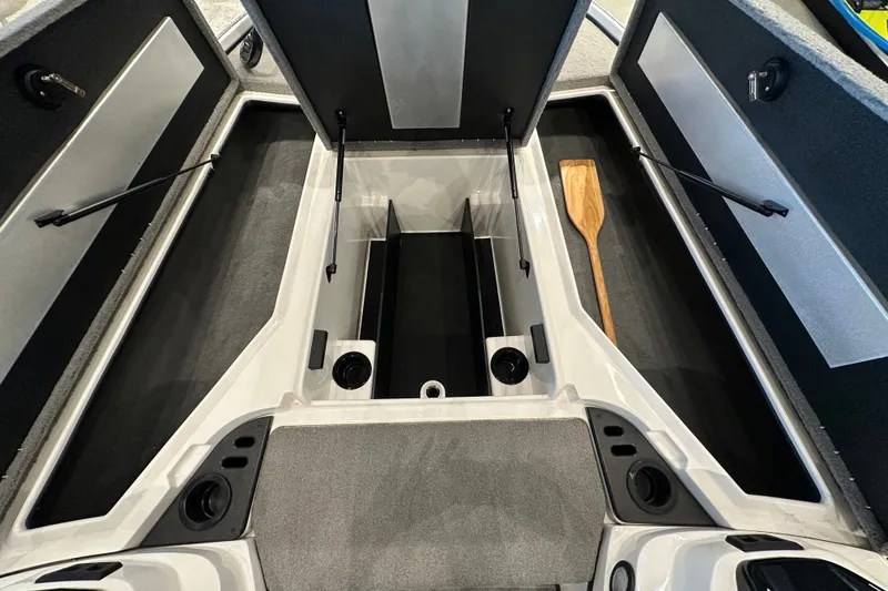 Slide: The Image of 2025 Nitro Z18 boat storage compartments with open lids and a wooden paddle inside. - 14