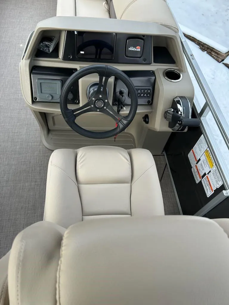 Slide: The Image of 2025 Sun Tracker Party Barge 20 DLX helm with beige seating and control panel. - 3