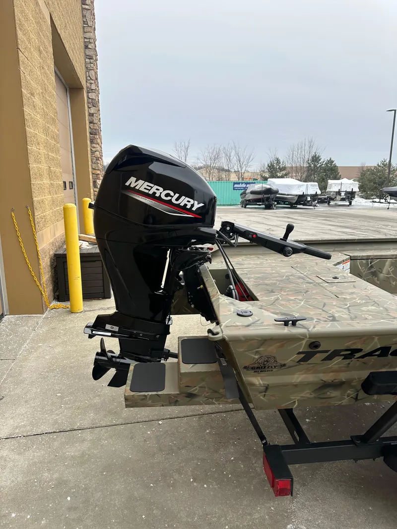 Slide: The Image of 2025 Tracker Grizzly 1654 T Sportsman with Mercury outboard motor, parked outdoors. - 3