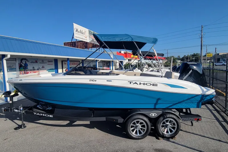 The Image of 2025 Tahoe 210 S boat with blue hull on trailer, parked outdoors. - 0
