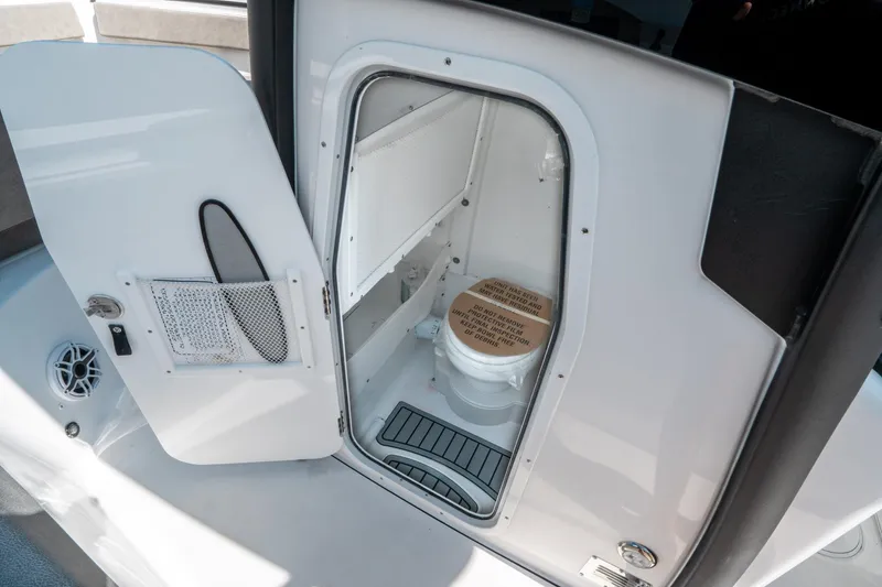 Slide: The Image of 2025 Sea Hunt Gamefish 25 boat interior with open door revealing compact marine toilet. - 29