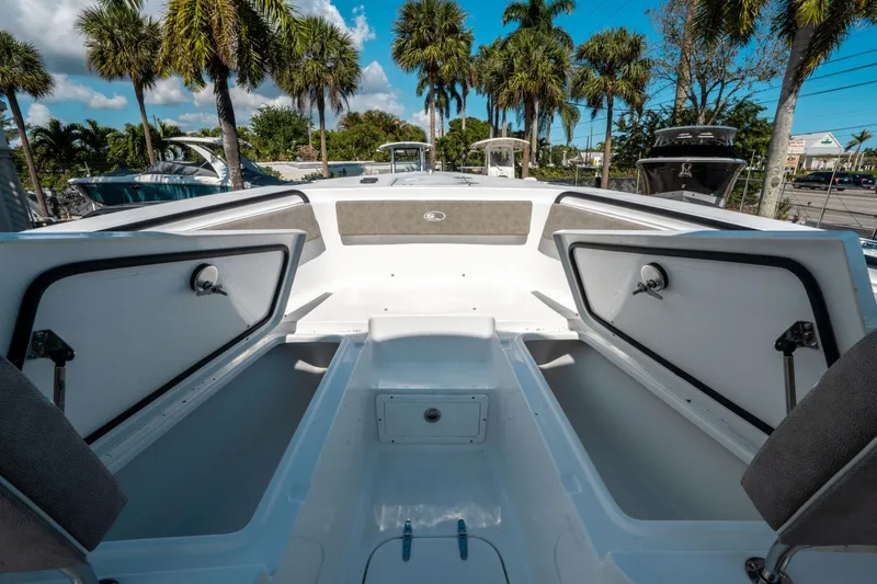 Slide: The Image of 2025 Sea Hunt Gamefish 25 boat interior with open storage compartments, surrounded by palm trees. - 35
