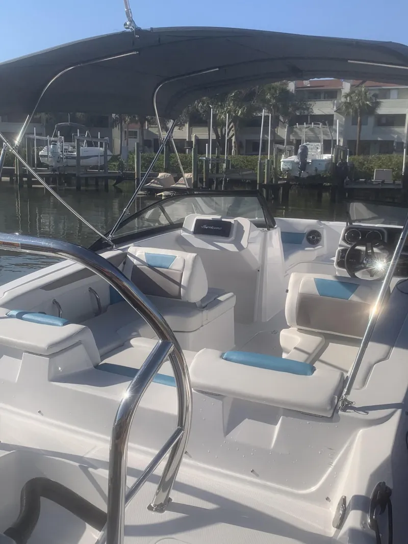 Slide: The Image of 2025 Hurricane SD 2050 boat with seating, steering wheel, and canopy in a marina setting. - 8