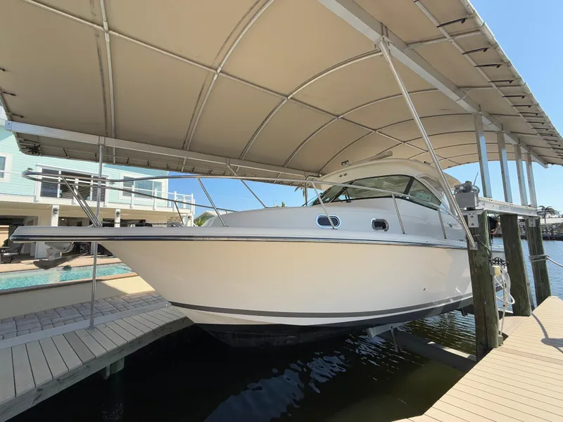 The Image of 2011 Pursuit OS 345 Offshore boat docked under a canopy. - 0