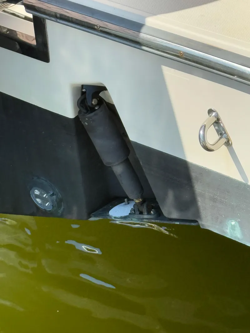 Slide: The Image of 2011 Pursuit OS 345 Offshore boat detail with hydraulic component near water. - 29