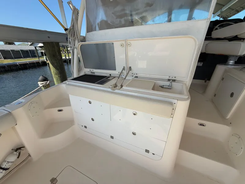 Slide: The Image of 2011 Pursuit OS 345 Offshore boat docked near a poolside, showcasing sleek design and amenities. - 4
