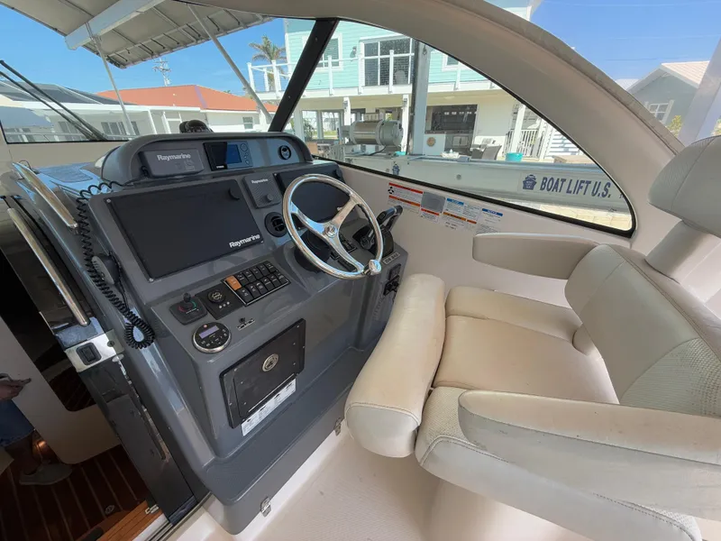 Slide: The Image of 2011 Pursuit OS 345 Offshore boat deck with storage and seating, docked by the water. - 5