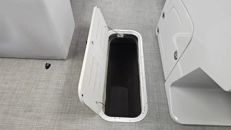 Slide: The Image of 2025 Bentley Pontoons Legacy 223 Swingback storage compartment, open on textured flooring. - 8