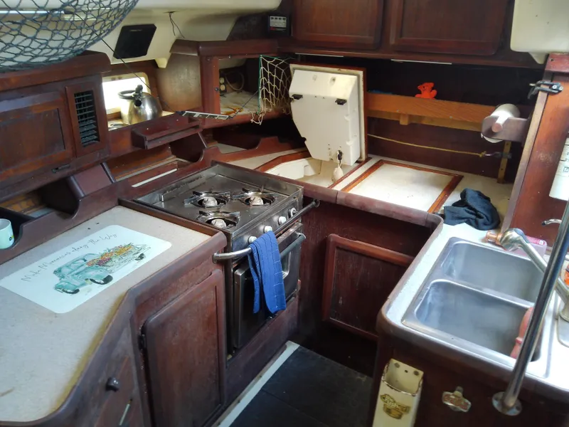 Slide: The Image of 1990 Hunter Passage 42 yacht kitchen with stove, sink, and wooden cabinetry. - 28