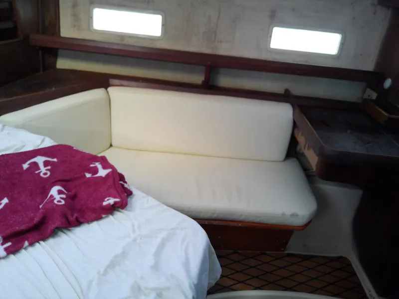 Slide: The Image of Interior of 1990 Hunter Passage 42 yacht with white sofa and red blanket. - 42