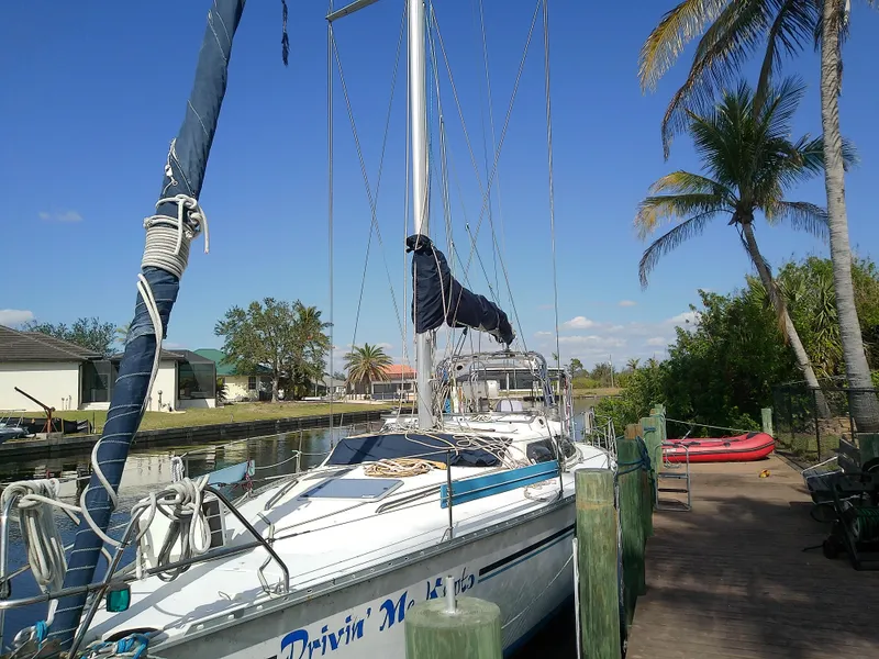Slide: The Image of Hunter Passage 42 sailboat docked, 1990 model, with palm trees and clear sky background. - 6