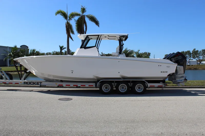 Slide: The Image of 2024 Fountain 32 NX boat on trailer, parked near palm trees. - 10