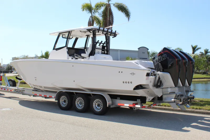 Slide: The Image of 2024 Fountain 32 NX boat on trailer, parked near palm trees. - 12