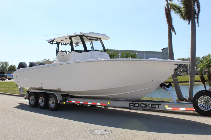 Slide: The Image of 2024 Fountain 32 NX boat on trailer, parked near palm trees. - 14