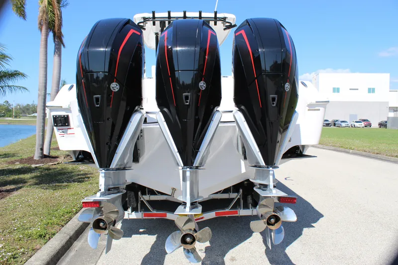 Slide: The Image of 2024 Fountain 32 NX boat with triple outboard engines, parked on a sunny day. - 24