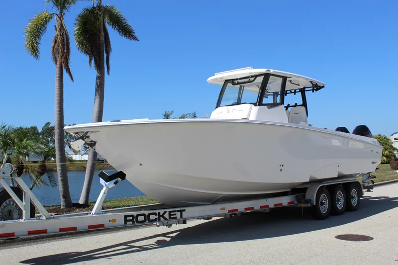 Slide: The Image of 2024 Fountain 32 NX boat on trailer, parked near palm trees and water. - 5
