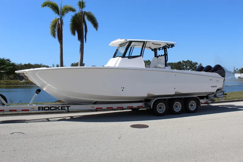 Slide: The Image of 2024 Fountain 32 NX boat on trailer, parked near palm trees and water. - 8