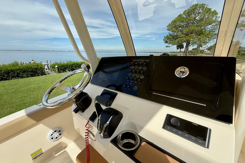 Slide: The Image of 2025 Scout 240 XSF boat dashboard with steering wheel and control panel, overlooking scenic waterfront. - 15
