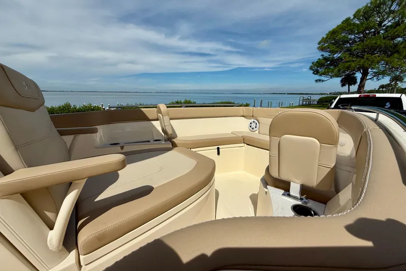 Slide: The Image of 2025 Scout 240 XSF boat interior with beige seating, overlooking a serene waterfront view. - 19