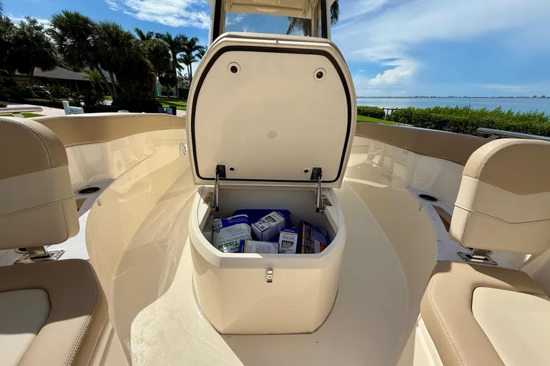 Slide: The Image of 2025 Scout 240 XSF boat with open storage compartment, scenic waterfront view. - 21