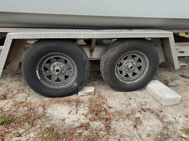 Slide: The Image of Trailer wheels supporting a 2019 World Cat 230 CC boat on sandy ground. - 19