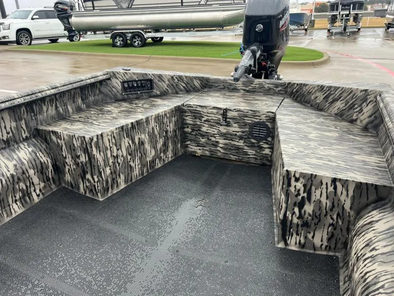Slide: The Image of 2025 Havoc Boats 1656 VJST interior with camo design and motor, parked on wet pavement. - 10