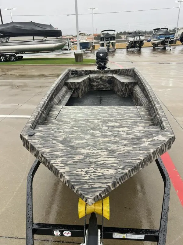 Slide: The Image of 2025 Havoc Boats 1656 VJST on trailer, camo design, parked outdoors. - 8