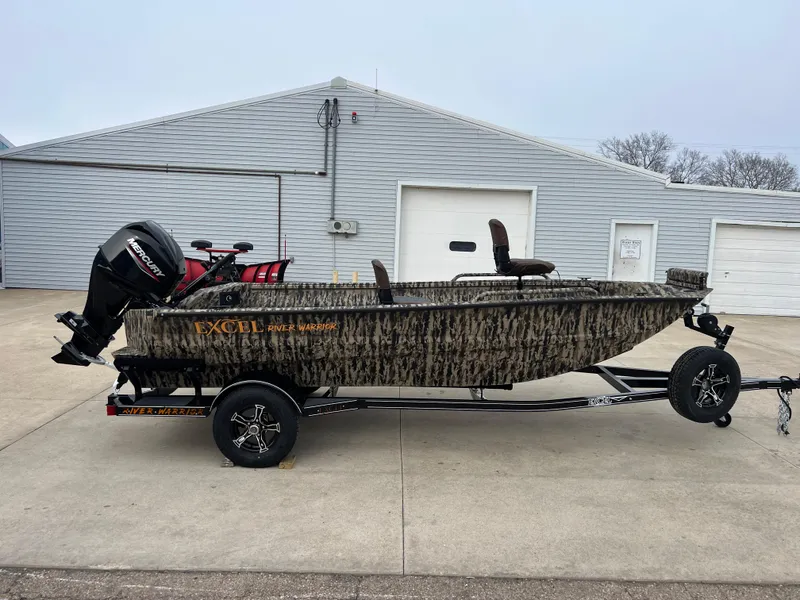 Slide: The Image of 2025 Excel 1651 River Warrior boat on trailer, camo design, parked outside a garage. - 0