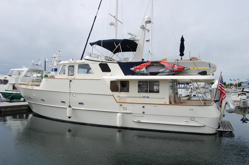 The Image of Eagle Pilothouse 2002 yacht docked in marina, featuring sleek design and American flag. - 0