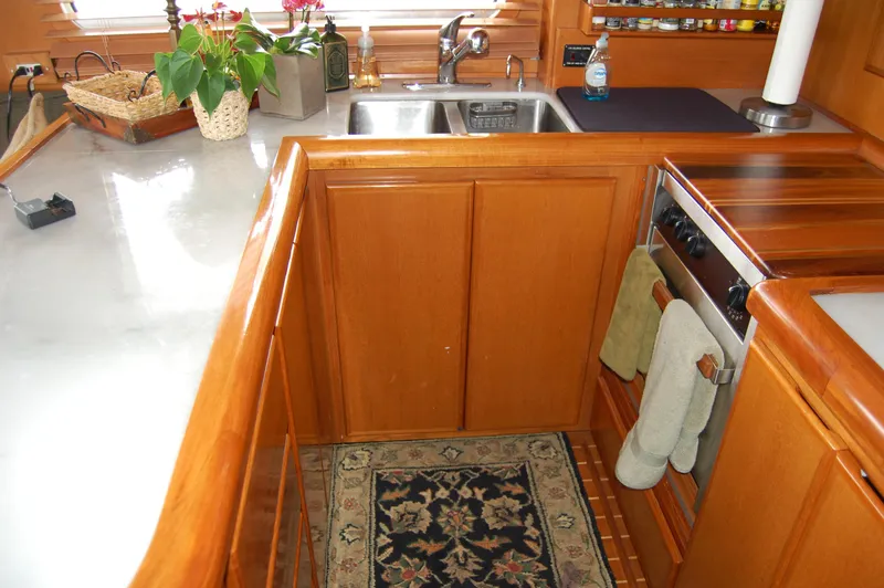Slide: The Image of 2002 Eagle Pilothouse kitchen with wooden cabinetry, sink, stove, and decorative rug. - 32