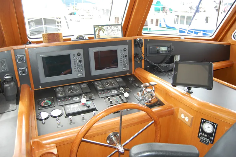 Slide: The Image of 2002 Eagle Pilothouse helm with navigation screens, wooden steering wheel, and control panels. - 38